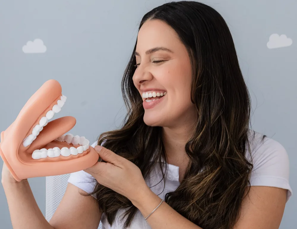 Dani rindo com uma boca gigante de brinquedo nas mãos